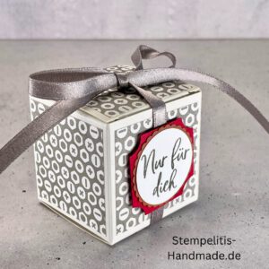 handdekorierte Geschenkschachtel mit Aufschrift „Nur für dich“, Geschenkschachtel mit grauem Muster und rotem Etikett, kleine Geschenkbox mit Satinband, Vorderansicht der Schachtel „Nur für dich“, offene Geschenkbox mit Inhalt, Detailaufnahme Schriftzug „Nur für dich“, stilvolle Geschenkverpackung mit Band